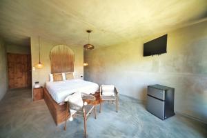 a bedroom with a bed and a tv and chairs at Dar Lamia Boutique Hotel - Adults Only in Manuel Antonio