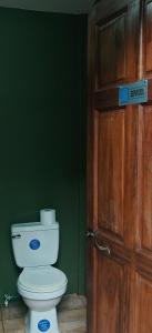 a bathroom with a toilet and a wooden door at Casa Perezosa in Parrita