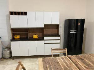a kitchen with white cabinets and a black refrigerator at Casa Ampla e aconchegante Limoeiro in Limoeiro