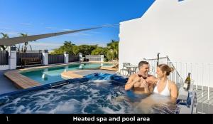 a man and woman sitting in a heated spa and pool area at Aaron Motel in Gladstone