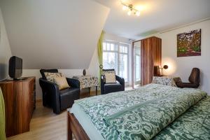 a bedroom with a bed and two chairs and a television at FH Luisenlund im Ostseebad Prerow in Prerow