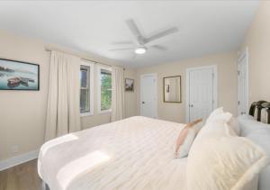a bedroom with a large white bed with a ceiling fan at Hill Top Forest Cabin with Hot Tub, Fire Pit & Screened Porch in Pigeon Forge +17 photos