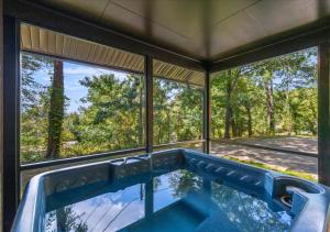 a swimming pool in a house with large windows at Hill Top Forest Cabin with Hot Tub, Fire Pit & Screened Porch in Pigeon Forge