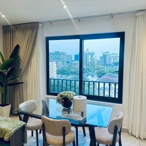 a dining room with a glass table and chairs and a large window at The Bantree by Tripview Apartments in Accra
