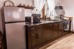 a kitchen with a stainless steel refrigerator and wooden cabinets at Cabana lui Matei in Borlova +8 photos