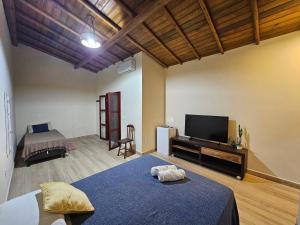 a bedroom with a bed and a television in a room at Suíte Bem Te vi in Porto Seguro