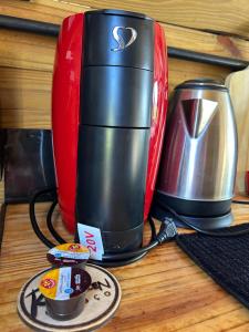 a red and black coffee maker on a table at Chalé aconchegante em madeira in Schroeder