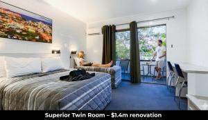 a woman sitting on a bed in a hotel room at Aaron Motel in Gladstone +4 photos