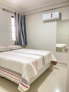 a white bedroom with a bed and a window at Apartamento 3 Quartos - Centro de Piratuba in Piratuba