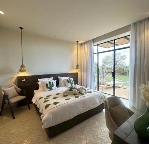 a bedroom with a large bed and a chair at villa Bohème Chic in Had Abdallah Rhiat