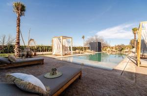 a swimming pool with a table and a couch next to it at villa Bohème Chic in Had Abdallah Rhiat