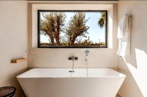 a large white tub in a bathroom with a window at villa Bohème Chic in Had Abdallah Rhiat +8 photos