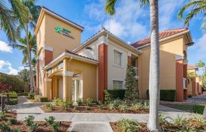 a building with palm trees in front of it at Extended Stay America Suites - Boca Raton - Commerce in Boca Raton