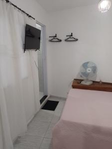 a bedroom with a bed and a tv and a fan at Vila Bárbara superior in Araruama