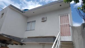 a white house with a stairway leading up to it at Vila Bárbara superior in Araruama