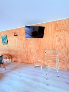 a room with a television on a wall with a ladder at Cabañas Agua y Campo in Osorno