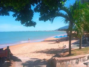 a man sitting on a bench on a beach at Hostel casa amarela in Rio das Ostras
