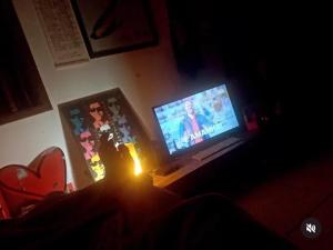 a person sitting in front of a television in a dark room at Hostel casa amarela in Rio das Ostras