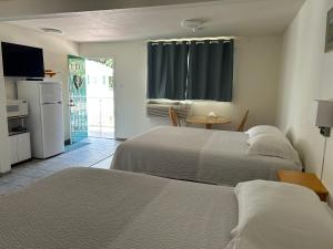 a bedroom with two beds and a table and a kitchen at Empire Motel in Penticton