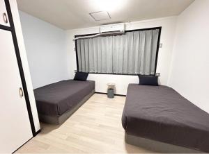 a bedroom with two beds and a window at 女性専用 dormitory all good in Miyako-jima +9 photos