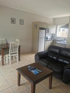 a living room with a black leather couch and a table at Reefton in Reefton