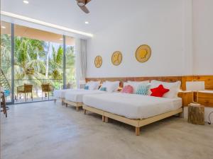 two beds in a room with large windows at Biosphere Beach in Dharavandhoo