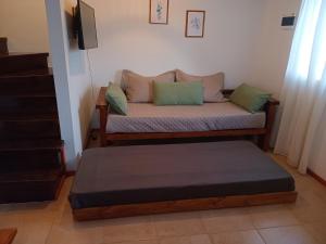 a couch with two pillows and a ottoman in a room at Cabañas del Oeste in San Carlos de Bariloche +2 photos