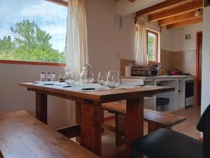 a wooden table with wine glasses on it in a kitchen at Cabañas del Oeste in San Carlos de Bariloche