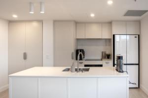 a kitchen with white cabinets and a sink at Chada by Cadiz Properties - 2 Bedroom Apartment with Lakeview Pool, within CBD and Beside Commonwealth Park in Canberra