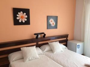 a bedroom with two white beds and two flowers on the wall at Pensión K-Hito in Santiago de la Ribera