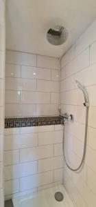 a shower in a bathroom with white tiled walls at Pension am Bach good Schlafi in Fuldatal