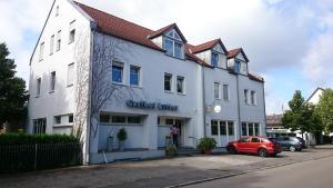a white building with a red car parked in front of it at Pension Lutter in Bodenwöhr