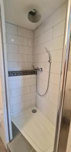 a white tiled bathroom with a shower with a bench at Pension am Bach good Schlafi in Fuldatal