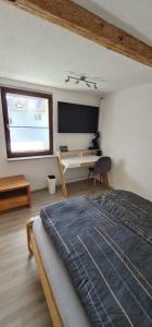 a bedroom with a bed and a desk and a window at Pension am Bach good Schlafi in Fuldatal