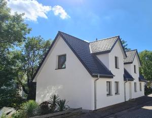 a white house with a black roof at Pension am Bach good Schlafi in Fuldatal