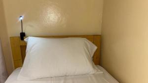 a bed with a white pillow with a light on it at 1 lit en dortoir partagé - Résidences PRIMIS Thiès in Thies