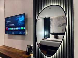 a mirror in a room with a bed and a tv at LION 12 Hotel in Can Tho