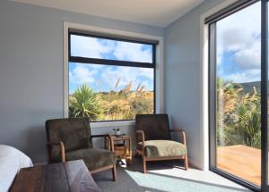a bedroom with two chairs and a table and a large window at Accomodation at Curio in Curio Bay