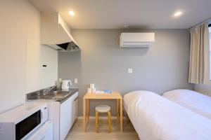 a small room with a bed and a table and a sink at Kohoku Apartment in Tokyo