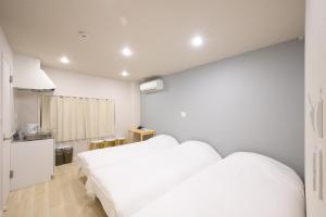 a bedroom with a large white bed and a kitchen at Kohoku Apartment in Tokyo