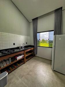 a kitchen with a sink and a refrigerator and a window at Pousada Ebenezer in Garopaba