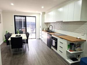 a kitchen with white cabinets and a table with chairs at No 3 Lakeside in Mulwala