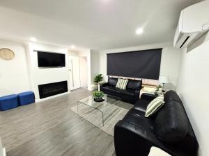 a living room with a black leather couch and a fireplace at No 3 Lakeside in Mulwala