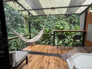 a hammock on a deck with a view of the jungle at River Paradise Cabin with Private Jacuzzi in Fortuna