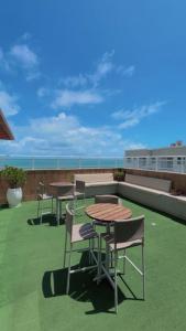 a patio with tables and chairs on a roof at Ap Mirante Fortaleza 5min da Praia com Piscina e Rooftop para 6 pessoas in Fortaleza