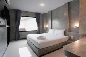a bedroom with a large white bed with a window at Ritsurin Boutique Hotel - โรงแรมริทสุริน บูติค in Phuket
