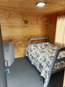 a small bedroom with a bed and a refrigerator at Hostal Egaña 228 in Puerto Montt