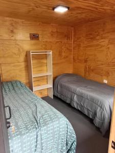 two beds in a room with wooden walls at Hostal Egaña 228 in Puerto Montt