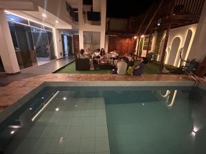 a group of people sitting around a pool in a building at Aura house in Huanchaco