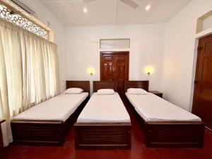 two twin beds in a room with a window at Bon Voyaage Villa in Trincomalee